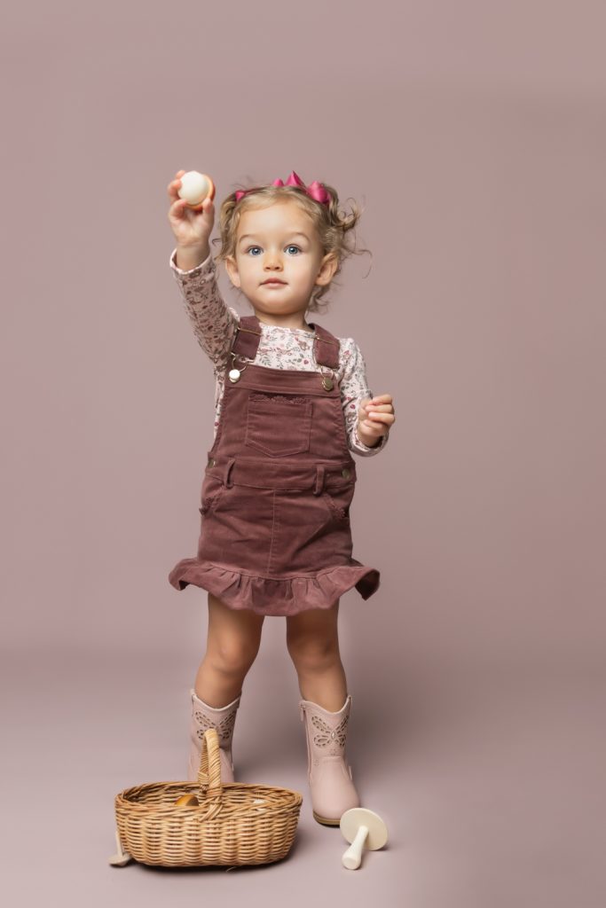 cute baby girl in clay pink corduroy dress during classic baby portrait with greensboro baby photographer