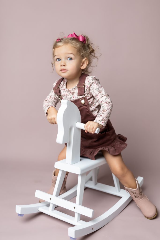 cute baby girl in clay pink corduroy dress during classic baby portrait with greensboro baby photographer