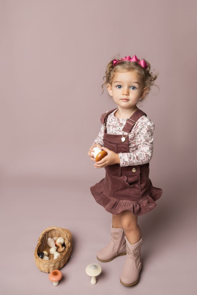 cute baby girl in clay pink corduroy dress during classic baby portrait with greensboro baby photographer