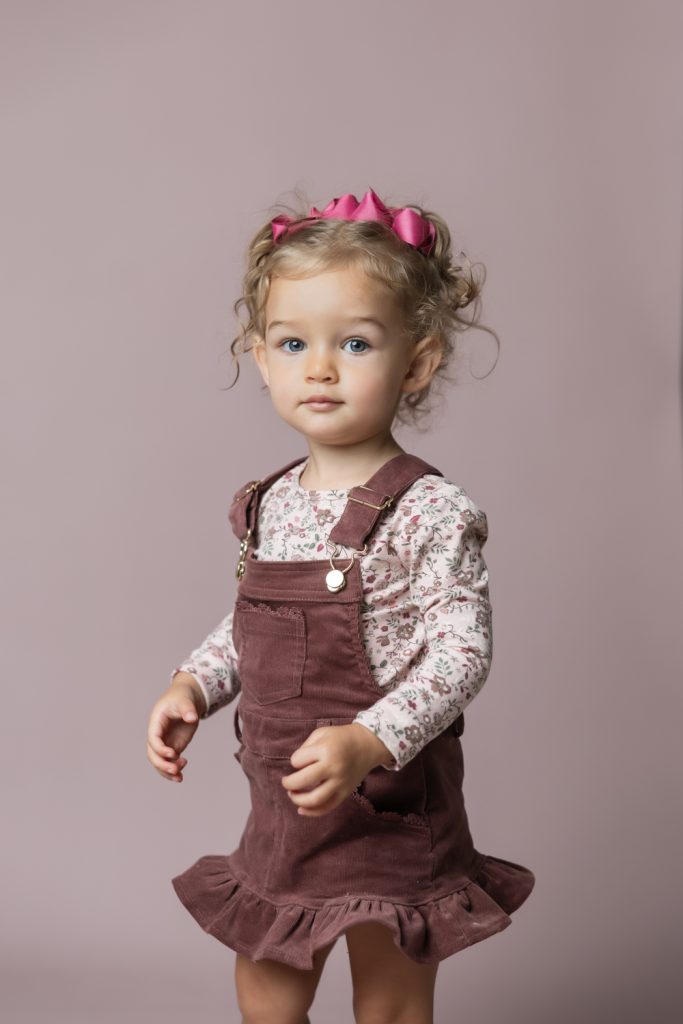 cute baby girl in clay pink corduroy dress during classic baby portrait with greensboro baby photographer