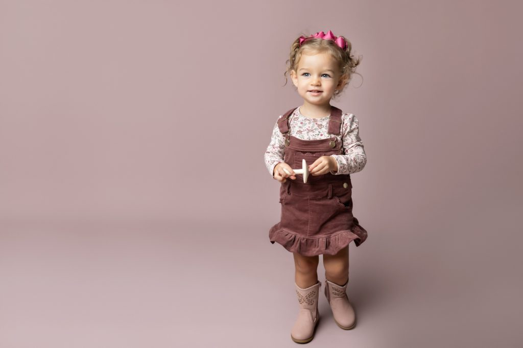 cute baby girl in clay pink corduroy dress during classic baby portrait with greensboro baby photographer
