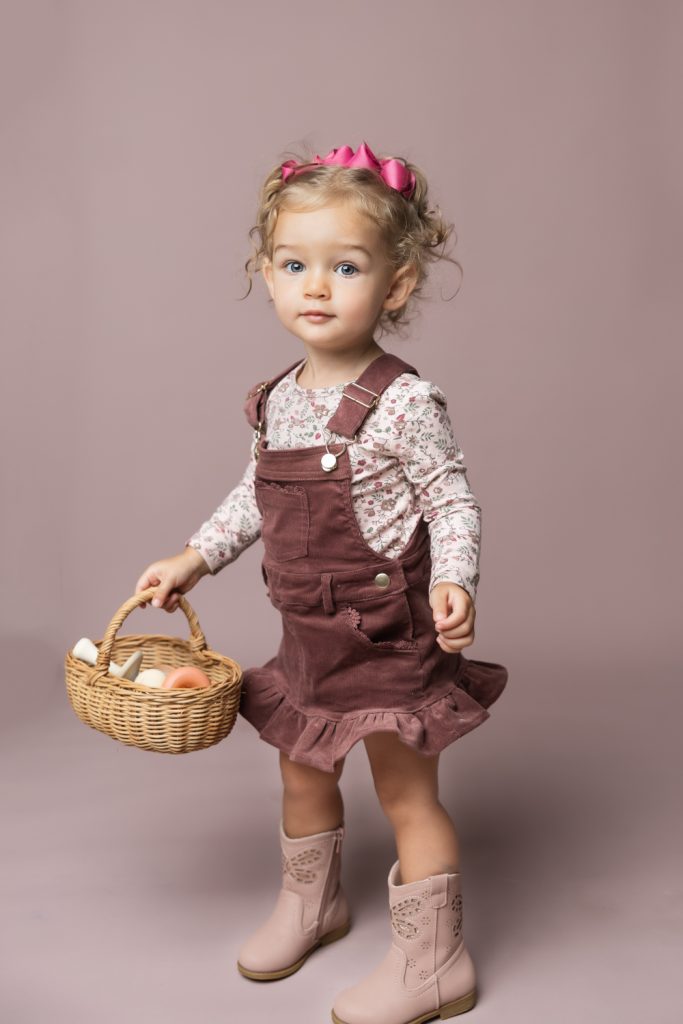 cute baby girl in clay pink corduroy dress during classic baby portrait with greensboro baby photographer