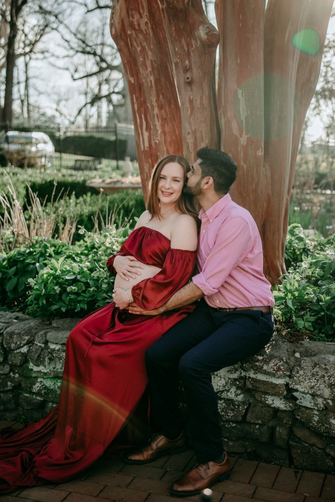 husband-kissing-wifes-temple-during-her-maternity-photo-session-at-Tanglewood-park-garden-winston-salem