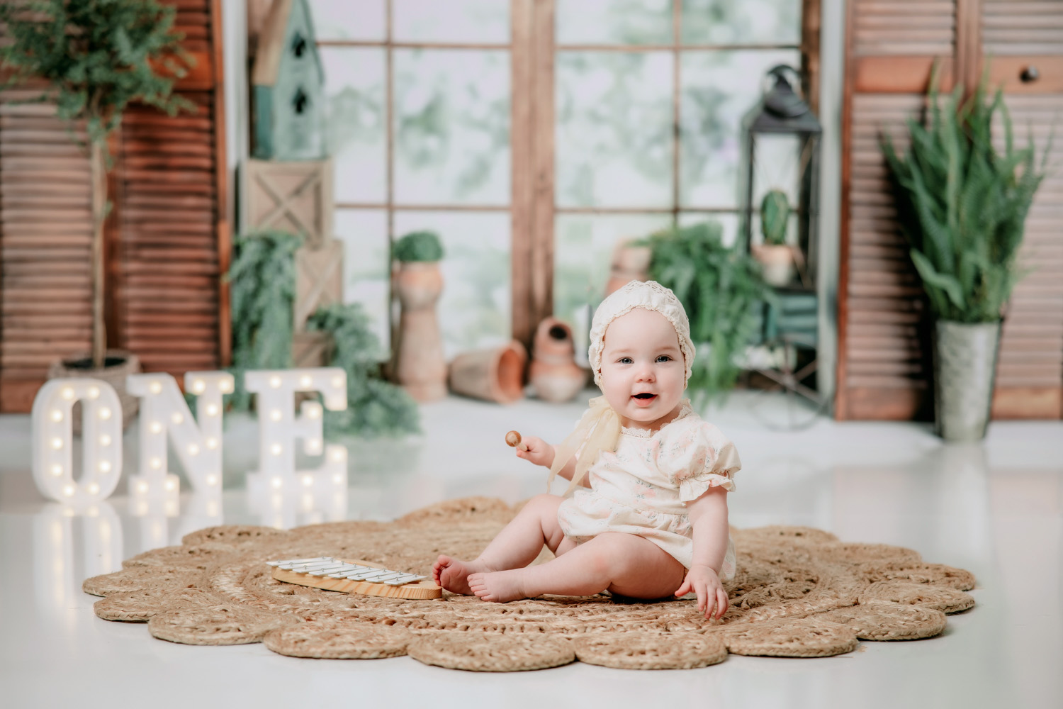 cute-baby-girl-boho-greenery-theme-first-birthday-photoshoot-in-front-of-window-in-winston-salem-photo-studio