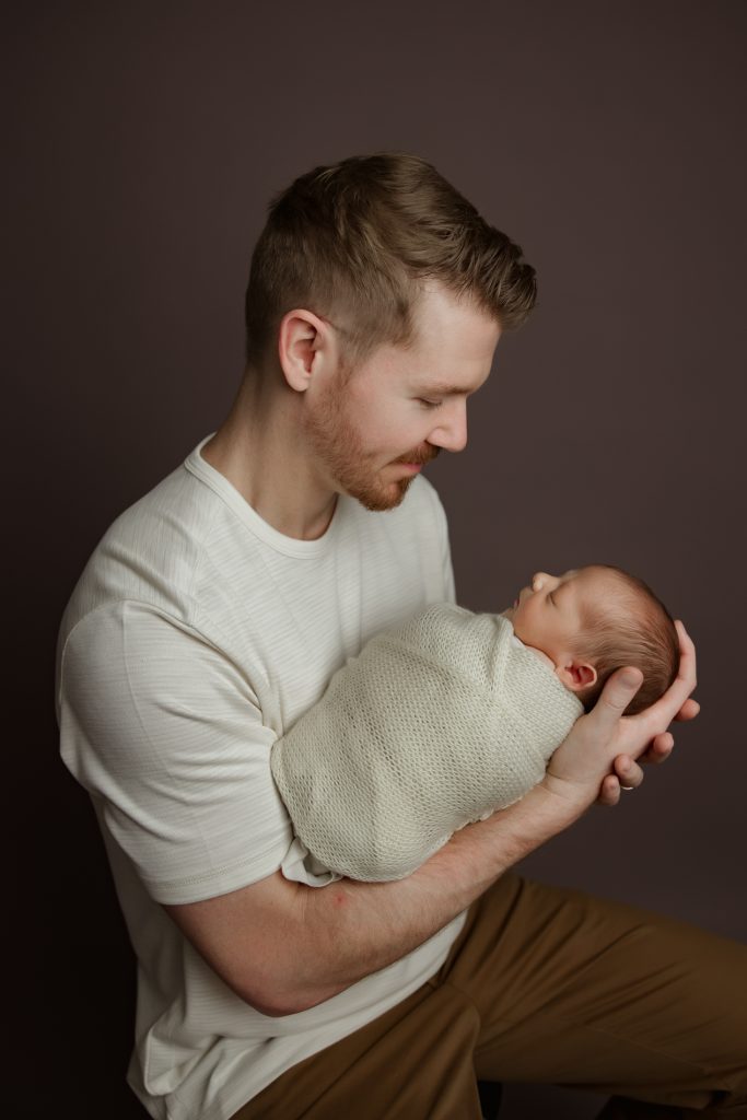 dad-holding-his-newborn-baby-twins-in-family-photo-during-winston-salem-newborn-photography-session