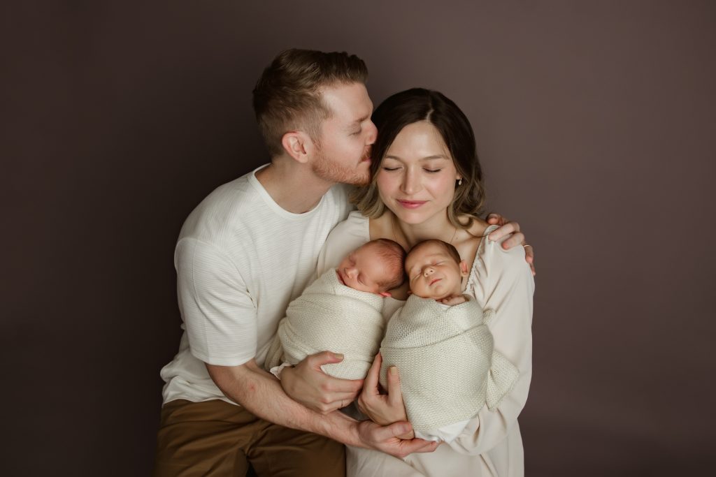 mom-and-dad-holding-their-newborn-baby-twins-in-family-photo-during-winston-salem-newborn-photography-session