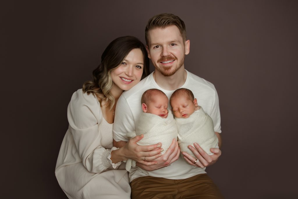 mom-and-dad-holding-their-newborn-baby-twins-in-family-photo-during-winston-salem-newborn-photography-session