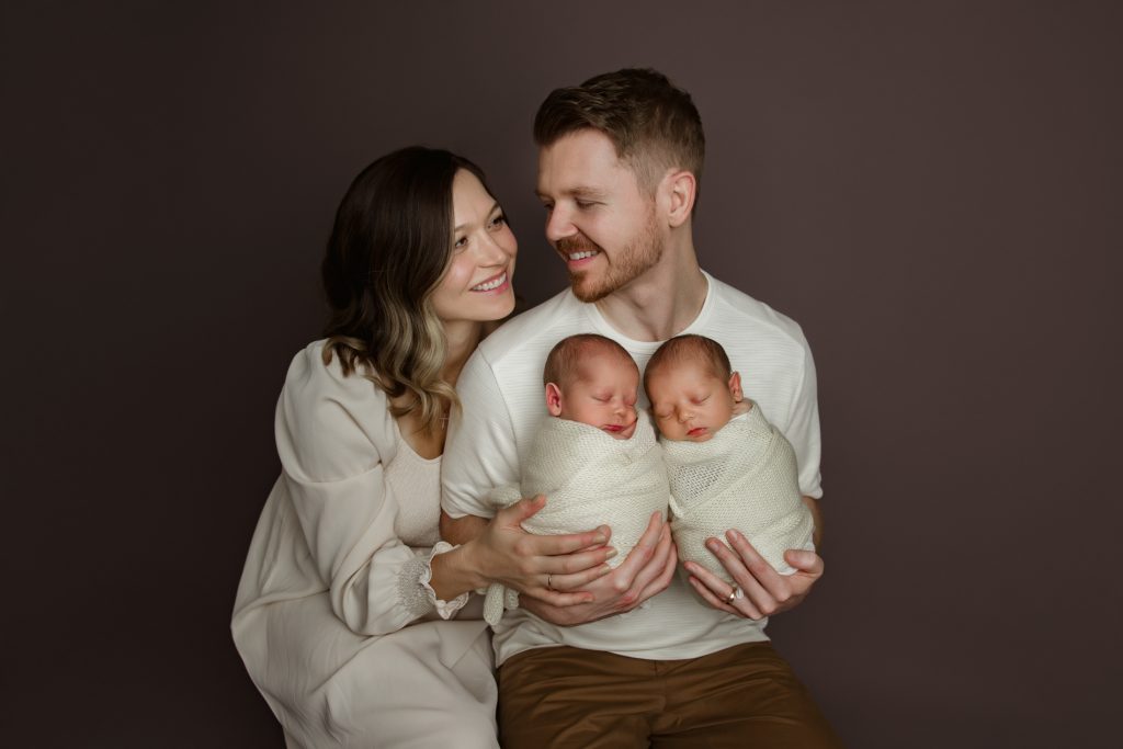 mom-and-dad-holding-their-newborn-baby-twins-in-family-photo-during-winston-salem-newborn-photography-session