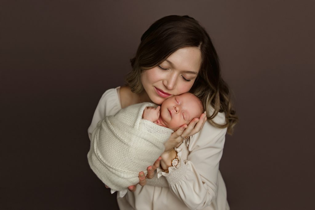 mother-holding-and-kissing-her-newborn-baby-in-family-photo-during-winston-salem-newborn-photo-session