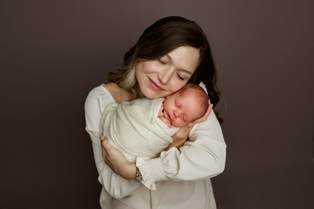 mother-holding-and-kissing-her-newborn-baby-in-family-photo-during-winston-salem-newborn-photo-session
