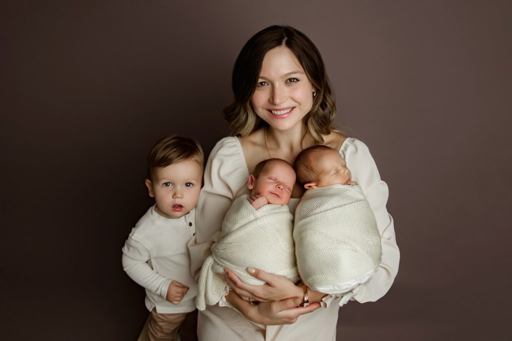 mother-holding-newborn-baby-twins-with-her-toddle-son-in-family-photo-during-winston-salem-newborn-photo-session