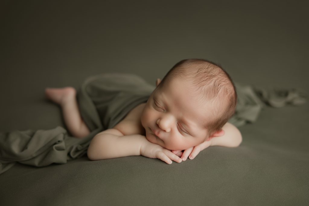 newborn-baby-boy-soundly-sleeping-on-green-blanket-during-winston-salem-newborn-photography-session