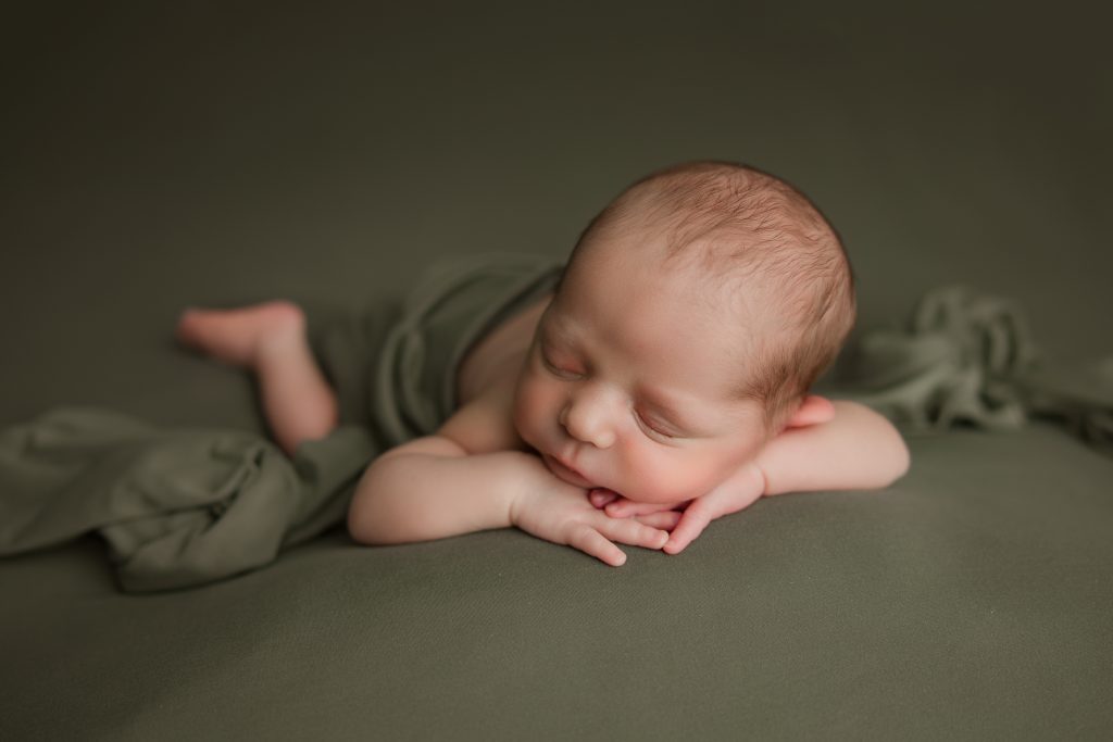 newborn-baby-boy-soundly-sleeping-on-green-blanket-during-winston-salem-newborn-photography-session