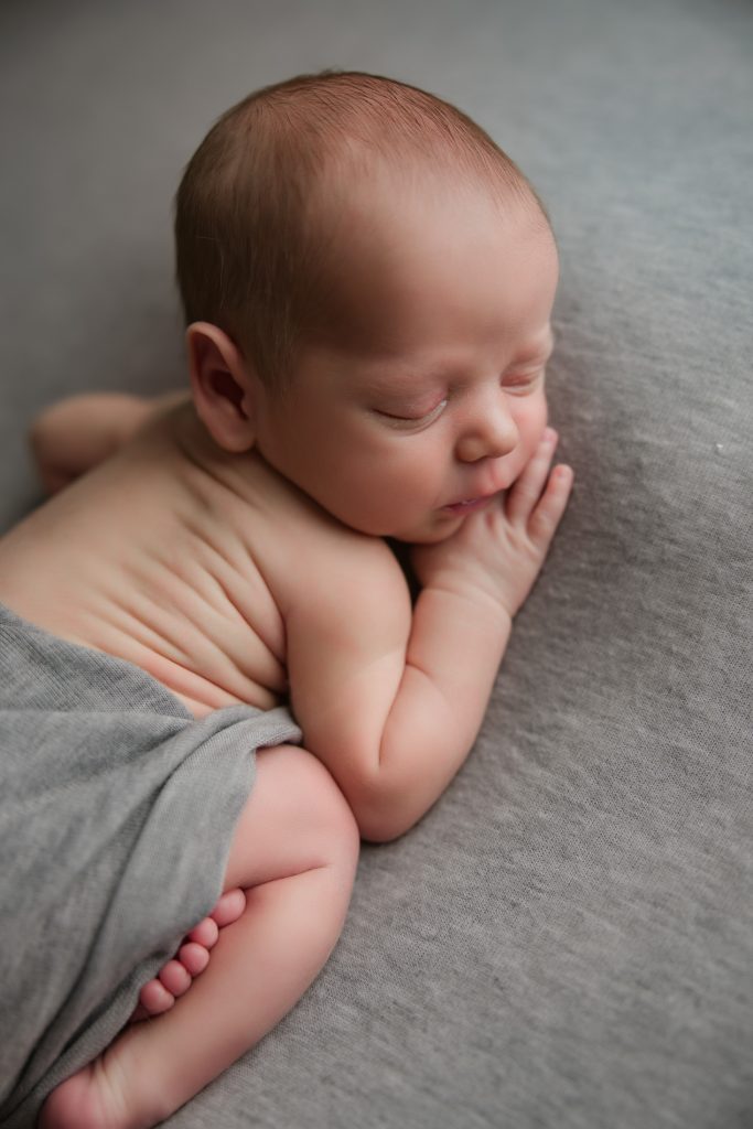 newborn-baby-boy-soundly-sleeping-on-grey-blanket-during-winston-salem-newborn-photography-session