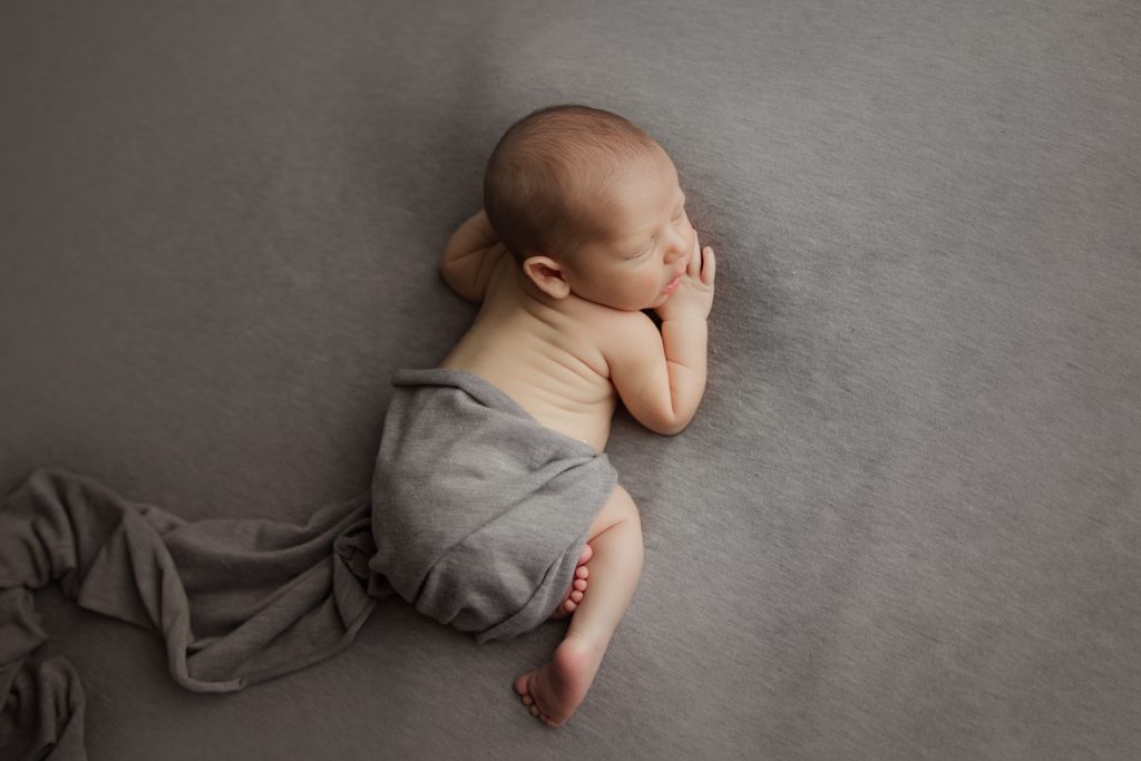newborn-baby-boy-soundly-sleeping-on-grey-blanket-during-winston-salem-newborn-photography-session
