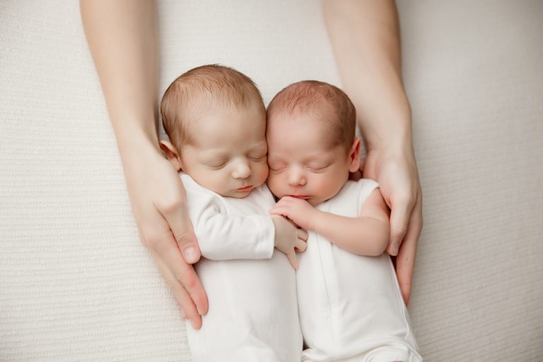 newborn-twin-boys-hugging-each-other-sleeping-in-white-blanket-during-winston-salem-newborn-photography-session