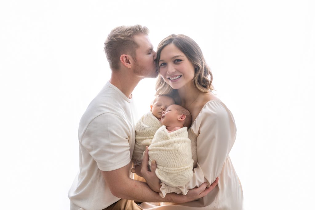 parents-holding-their-newborn-baby-twins-in-dreamy-backlit-family-photo-during-winston-salem-newborn-photography-session