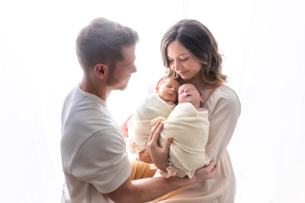 parents-holding-their-newborn-baby-twins-in-dreamy-backlit-family-photo-during-winston-salem-newborn-photography-session