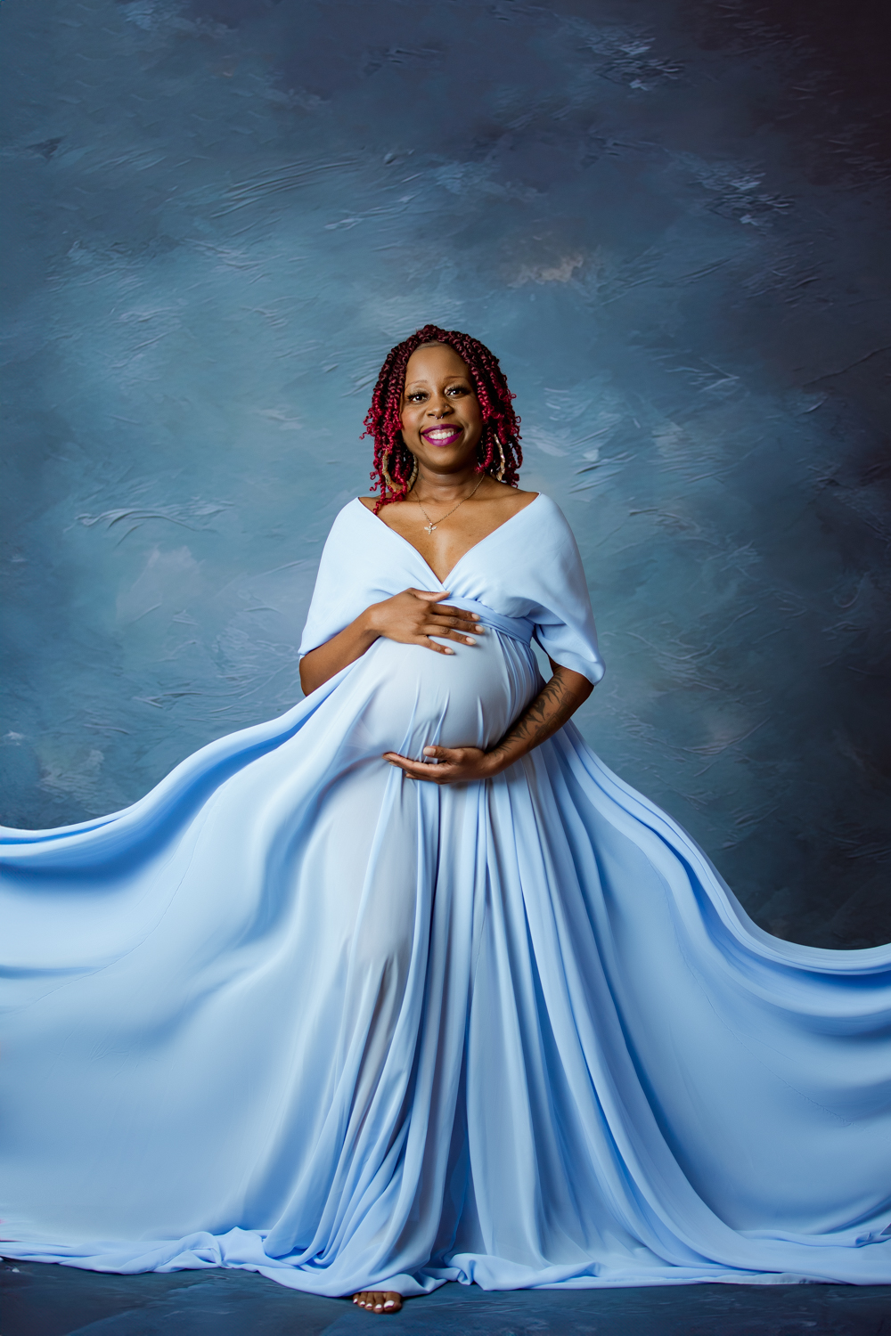 maternity mother wearing baby blue gown in blue fine art background during maternity photo session Winston Salem nc