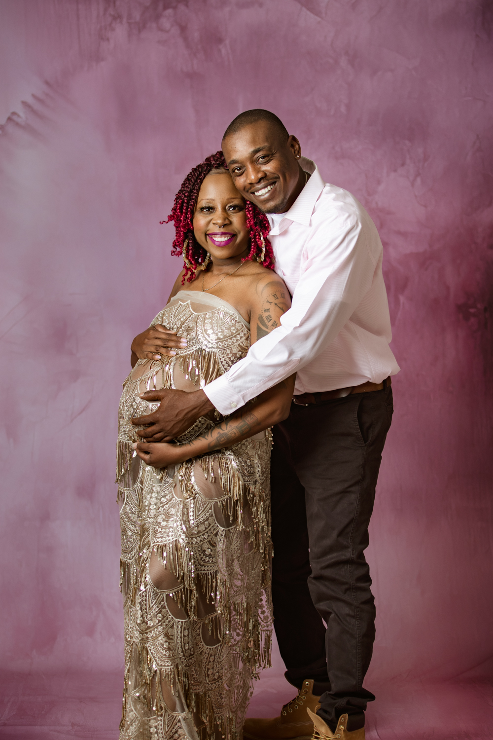 maternity mother wrapped in golden fabric with her husband in blue fine art background during maternity photo session Winston Salem nc