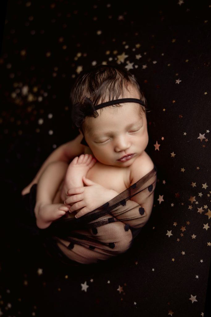 newborn-baby-girl-swaddled-in-black-lace-sleeping-on-stary-blanket-during-greensboro-newborn-photography-session