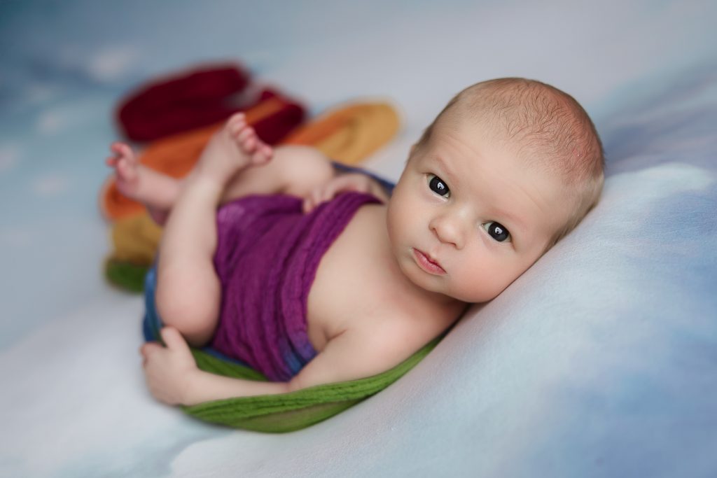 newborn-baby-boy-in-cloud-blanket-wrapped-in-rainbow-scarf-during-winston-salem-newborn-photography-session