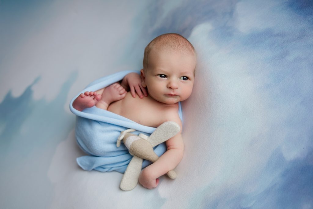 newborn-baby-boy-in-cloud-blanket-wrapped-in-rainbow-scarf-during-winston-salem-newborn-photography-session