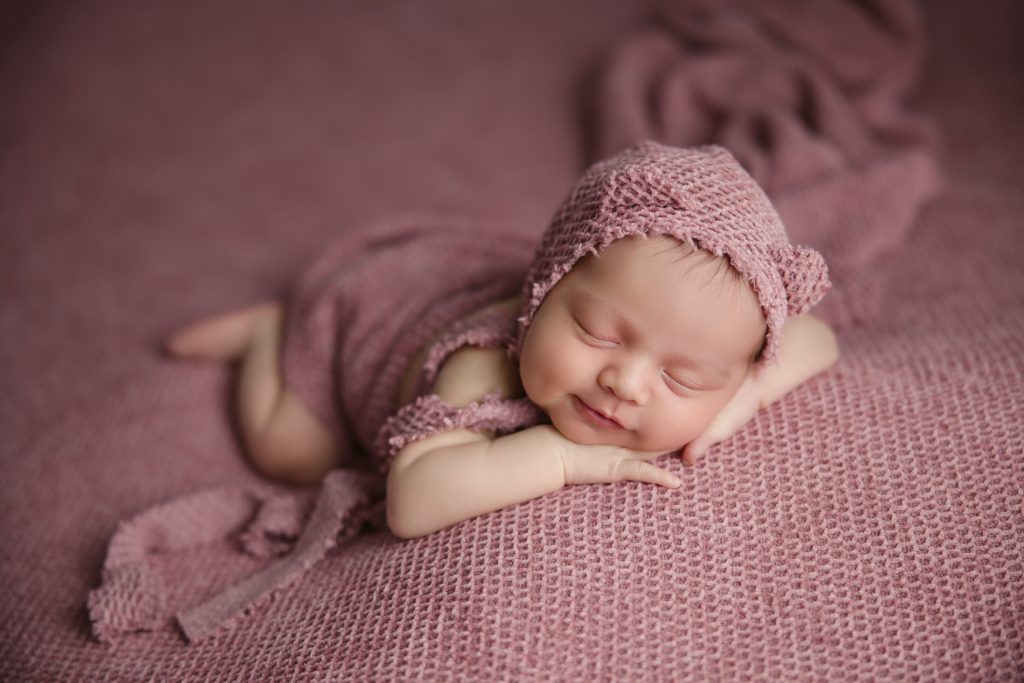 smiling newborn-baby-girl-photo-session-in pink background and pink outfit with-winston-salem-newborn-photographer
