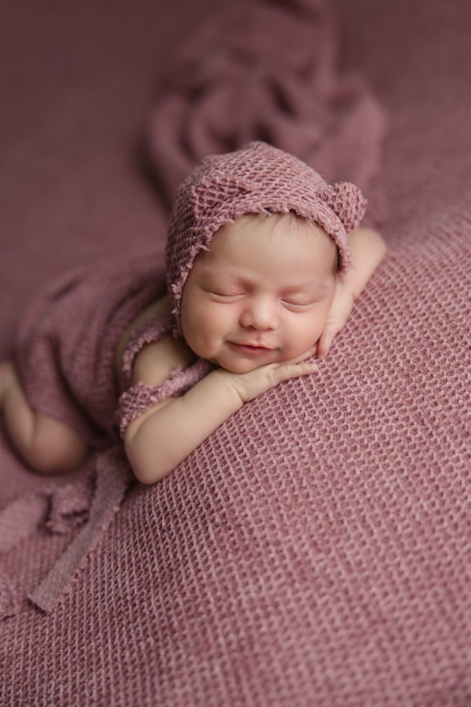 smiling newborn-baby-girl-photo-session-in pink background and pink outfit with-winston-salem-newborn-photographer
